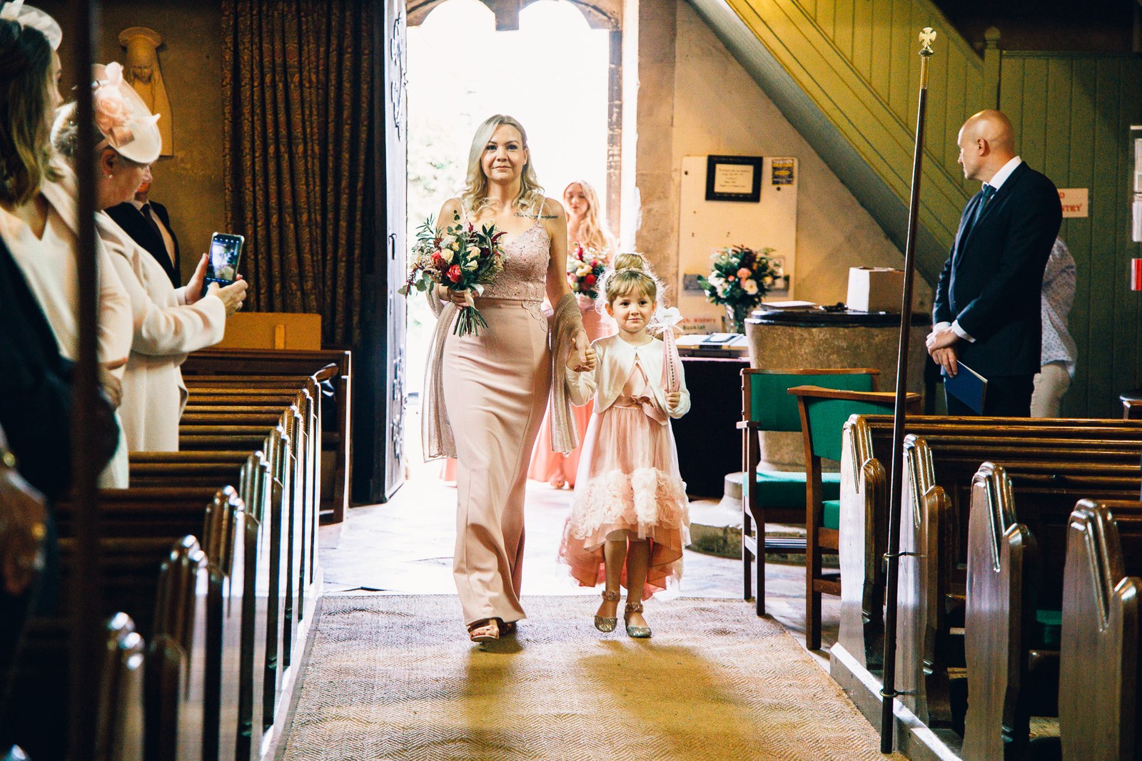 A bridesmaid and flower girl walking down the aisle at the church entrance