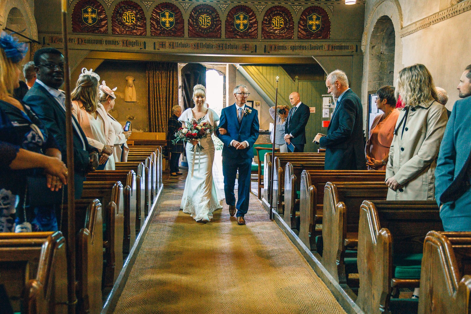 Bride walking down the aisle on her father's arm past standing guests