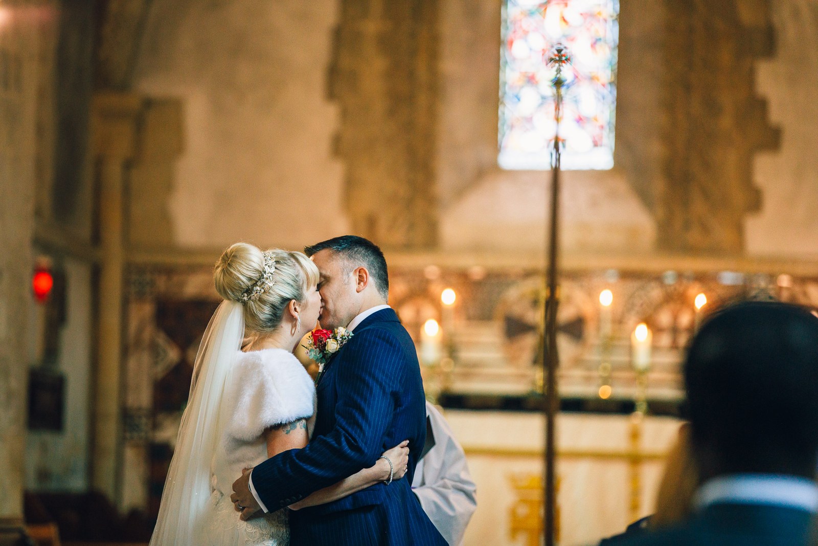 Bride and groom sharing their first kiss at the candlelit altar