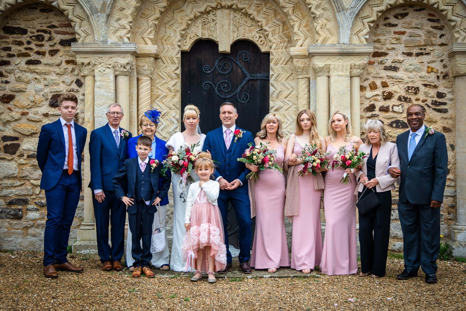 The full bridal party before the carved stone doorway of the church
