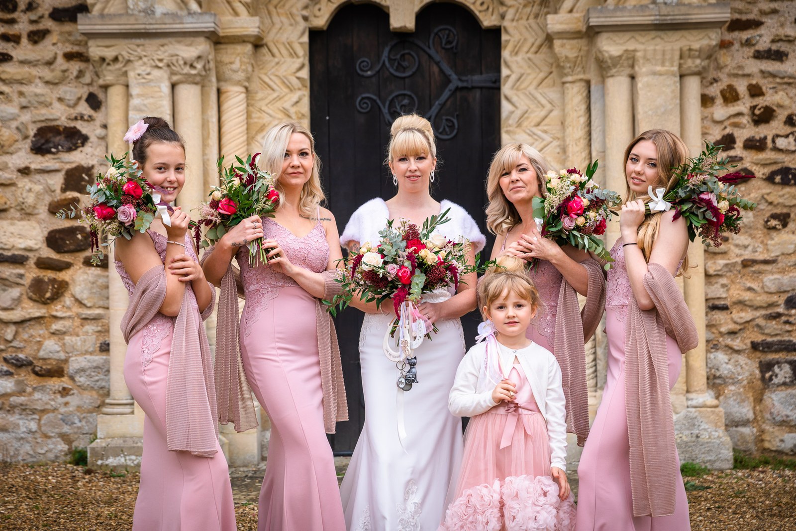 Bride with her pink bridesmaids and a flower girl at the church doorway