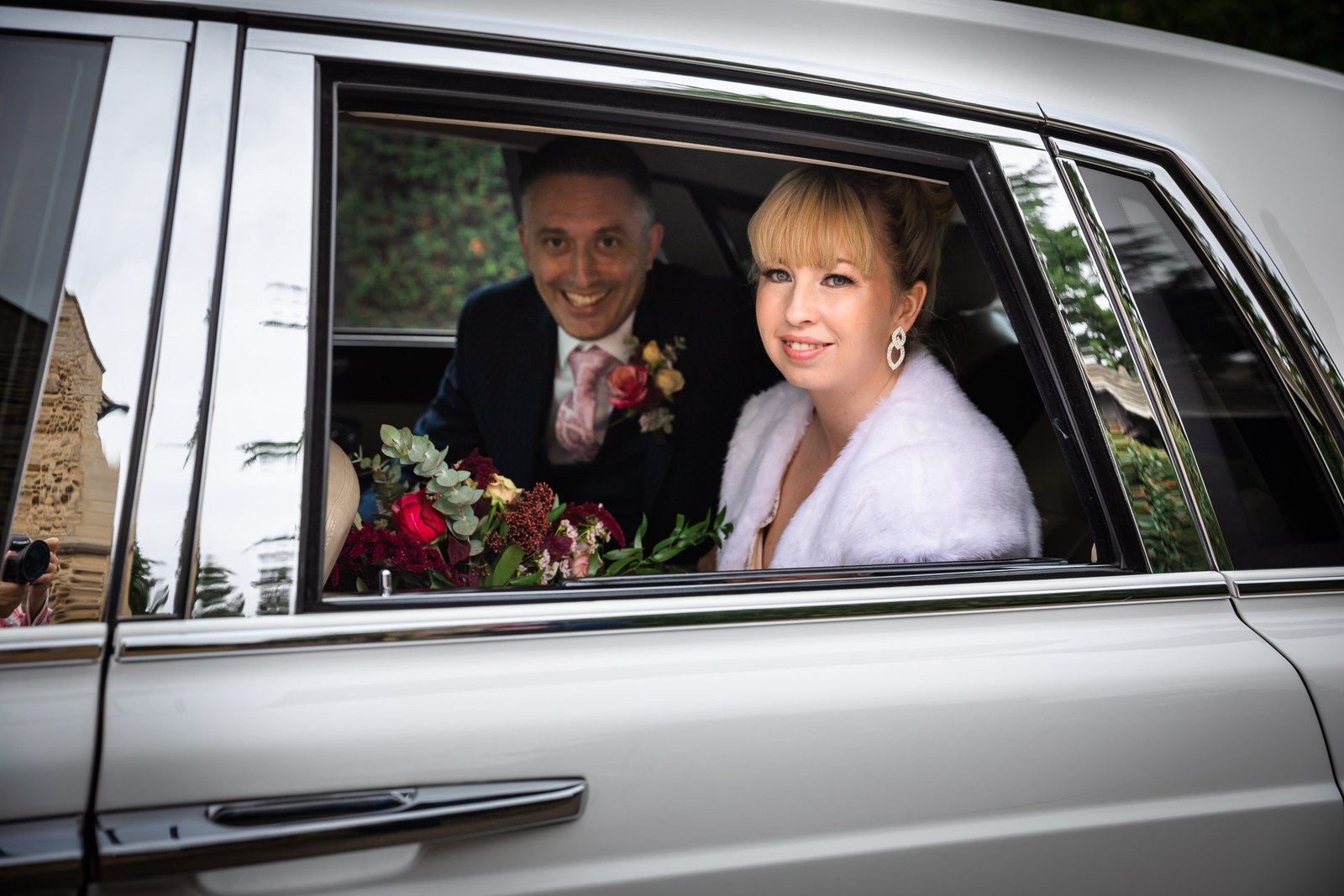 Bride and groom looking out of the wedding car window