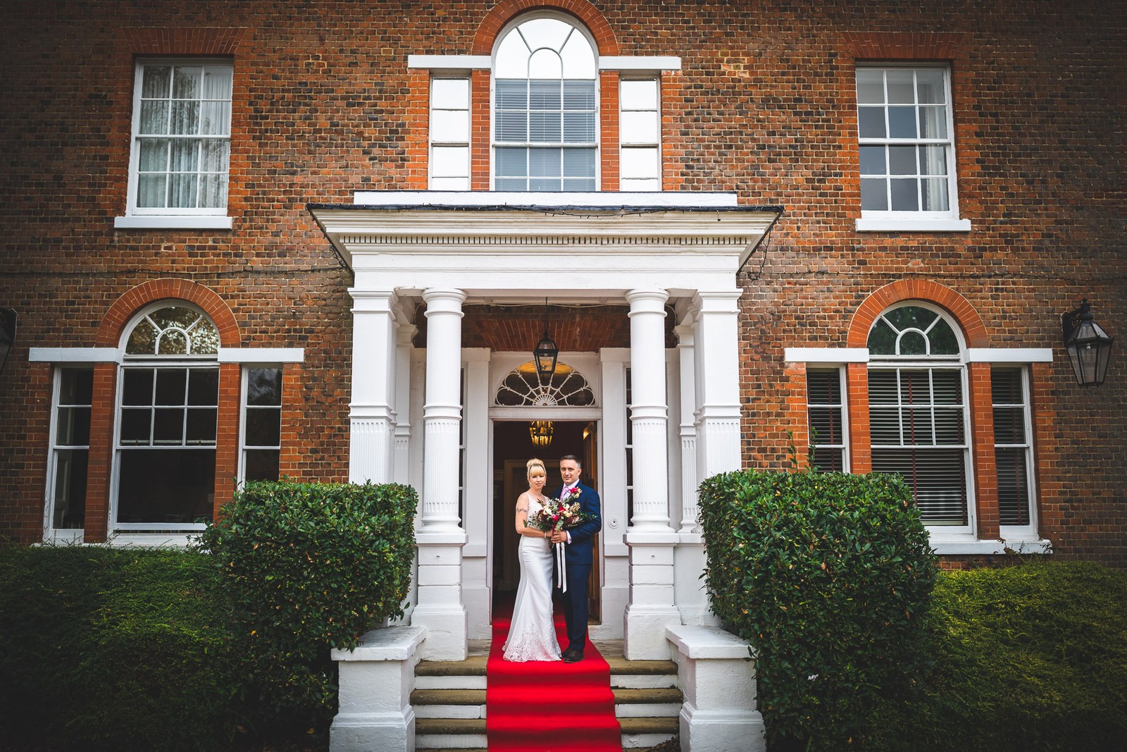 Bride and groom on the red-carpeted steps of Moore Place Hotel's columned entrance