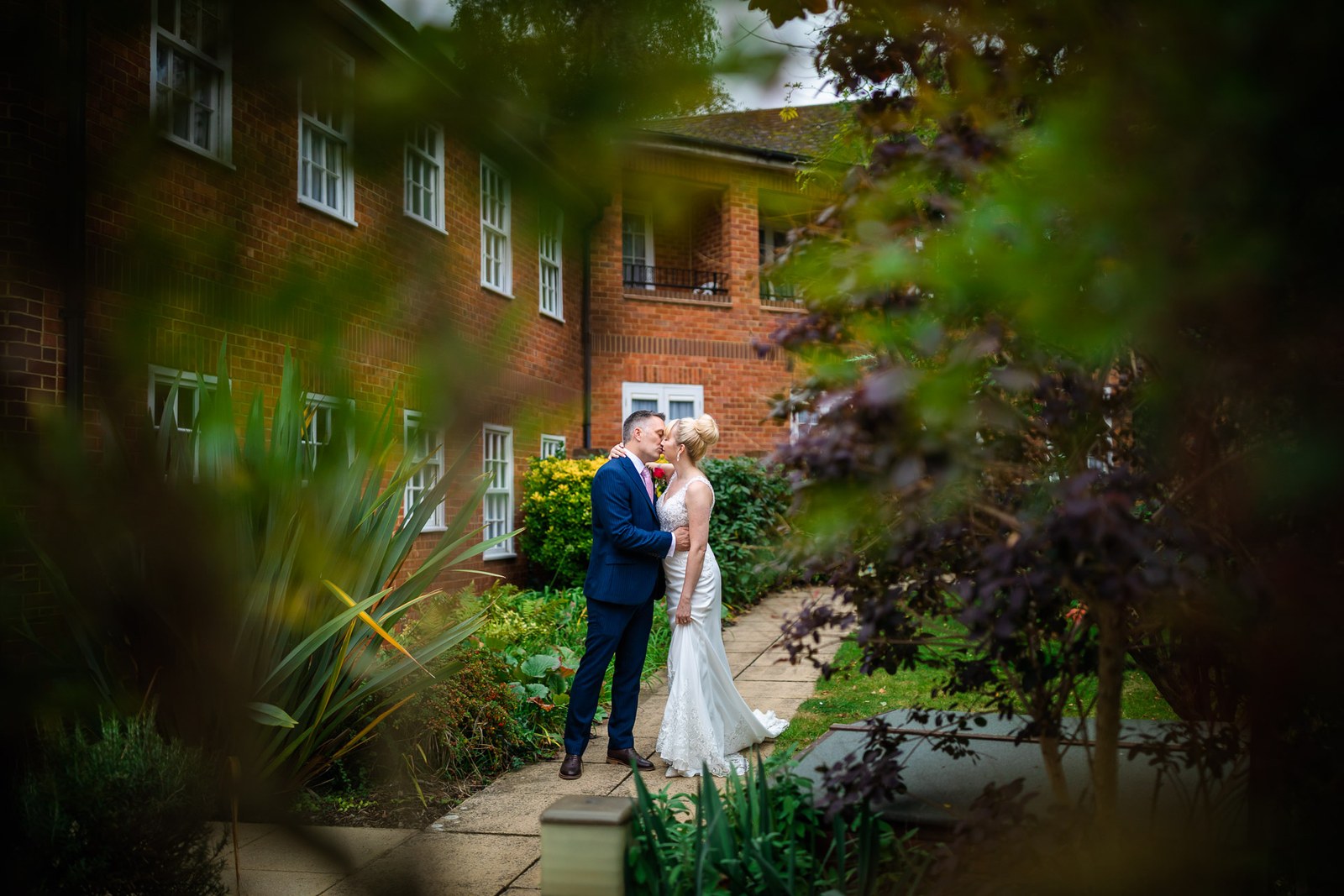 The couple embracing in the Moore Place Hotel garden, framed by foliage