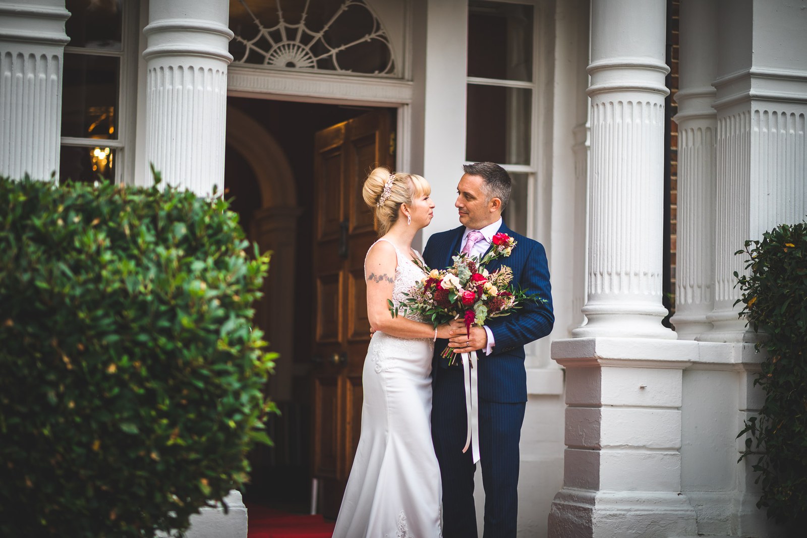 Bride and groom facing each other beneath the hotel's columned entrance portico