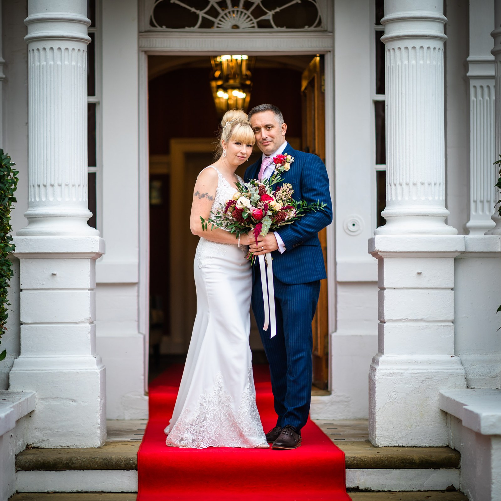 Bride and groom on the red carpet of Moore Place Hotel's columned doorway