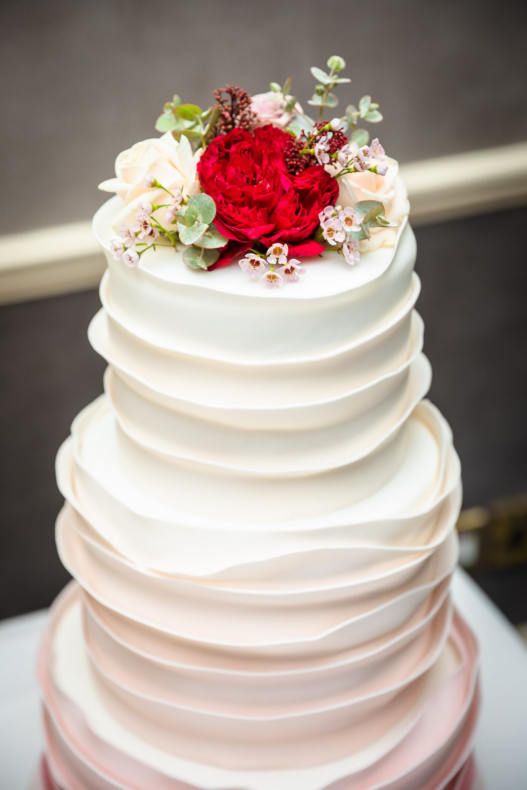 Close-up of the white ombre wedding cake topped with a red rose