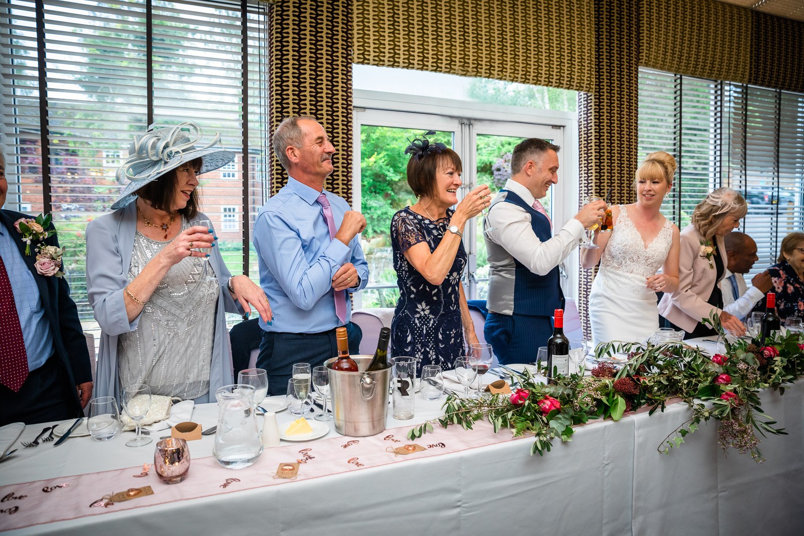The wedding party at the flower-draped top table during the toasts