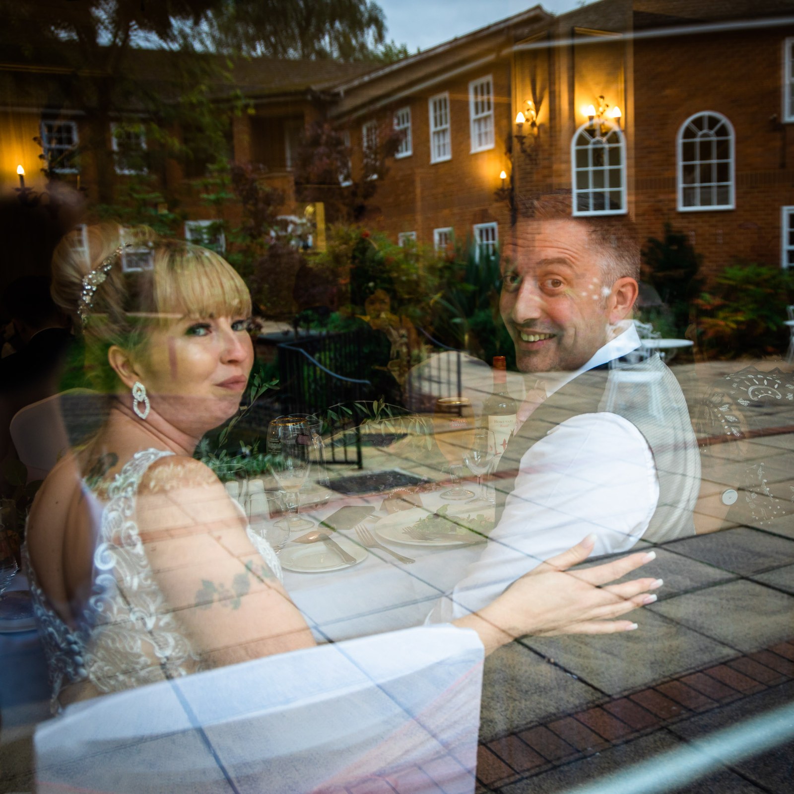 Reflection portrait of the couple mirrored in a window over the hotel courtyard