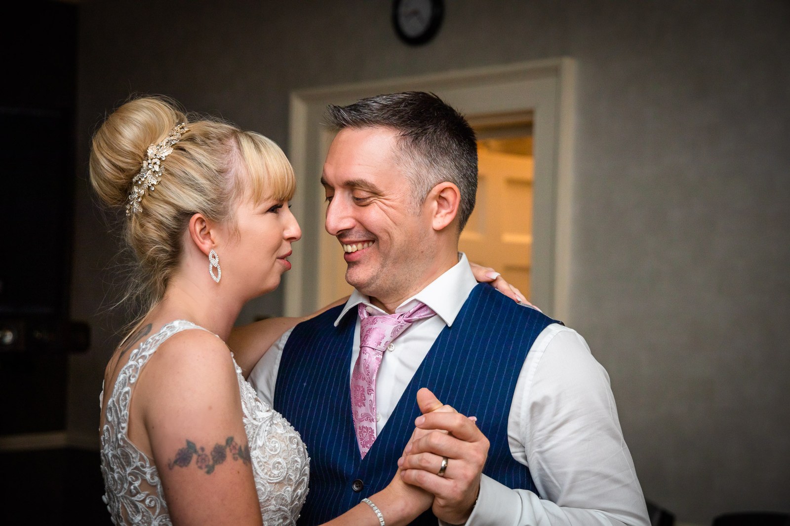 The couple dancing with foreheads close, the bride's arm around the groom
