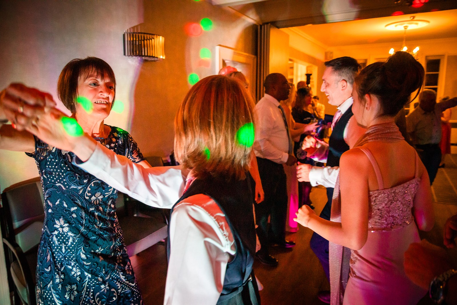 Guests dancing with arms outstretched under green disco lights