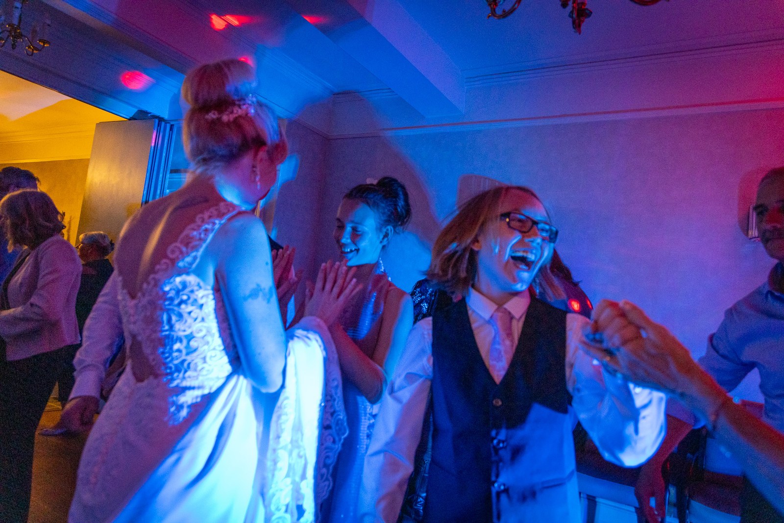 Bride dancing among the guests under blue and pink lighting