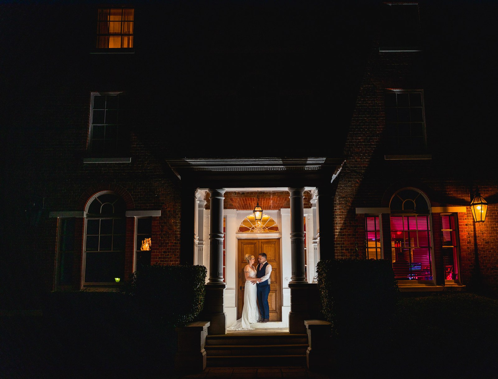 Night view of the illuminated Moore Place Hotel with the couple in the lit doorway