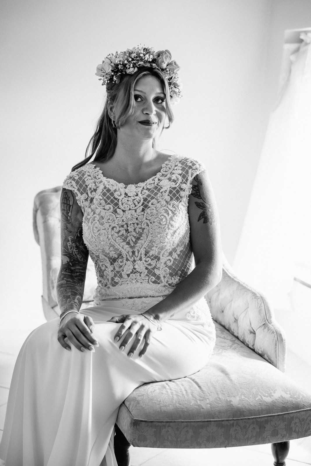 Black and white portrait of the bride in a flower crown on a velvet chair
