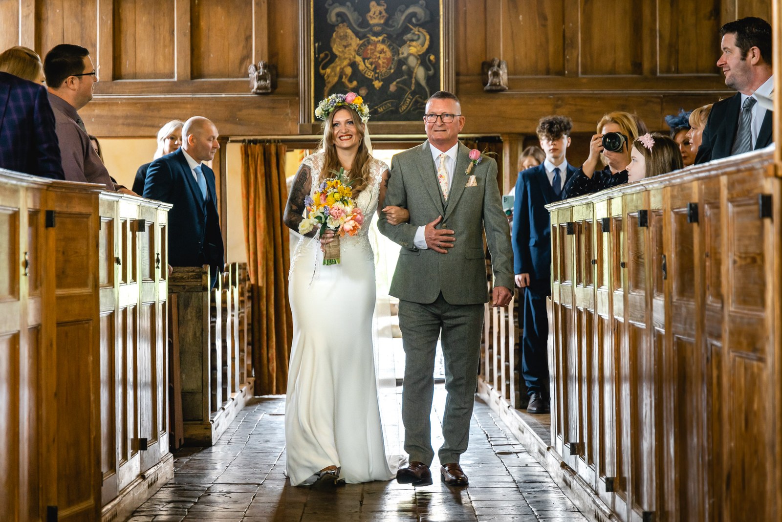 Bride walking down the aisle on her father's arm in the panelled church