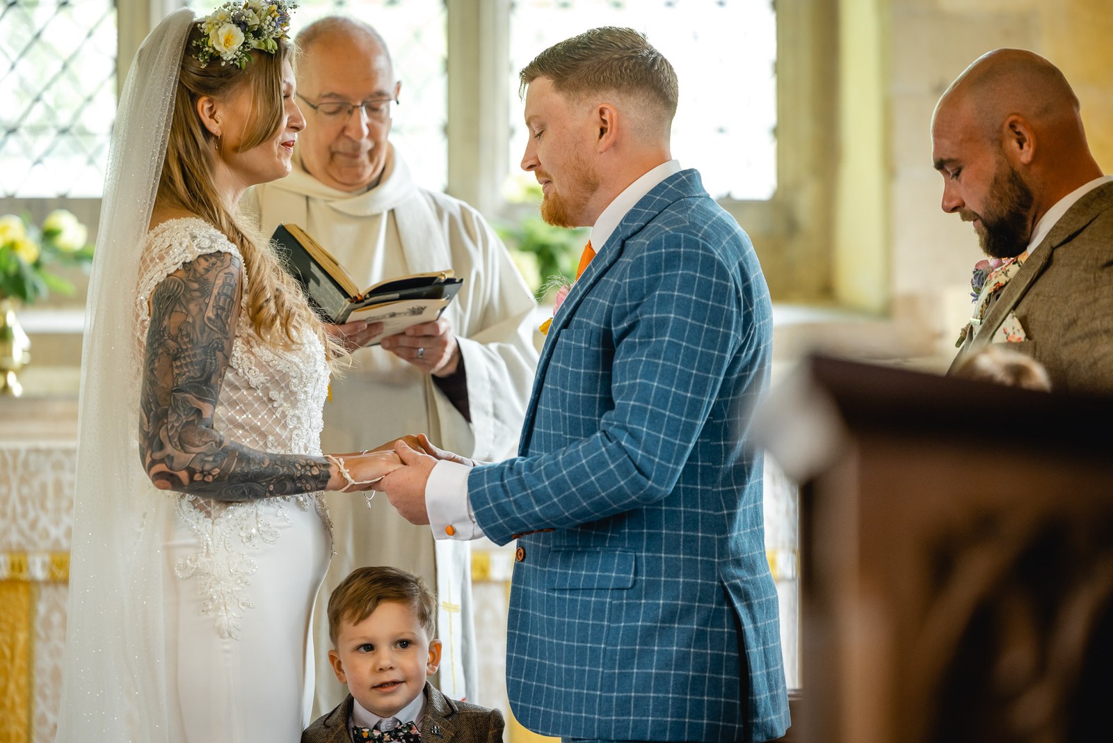 Bride and groom holding hands during the vows as the vicar reads