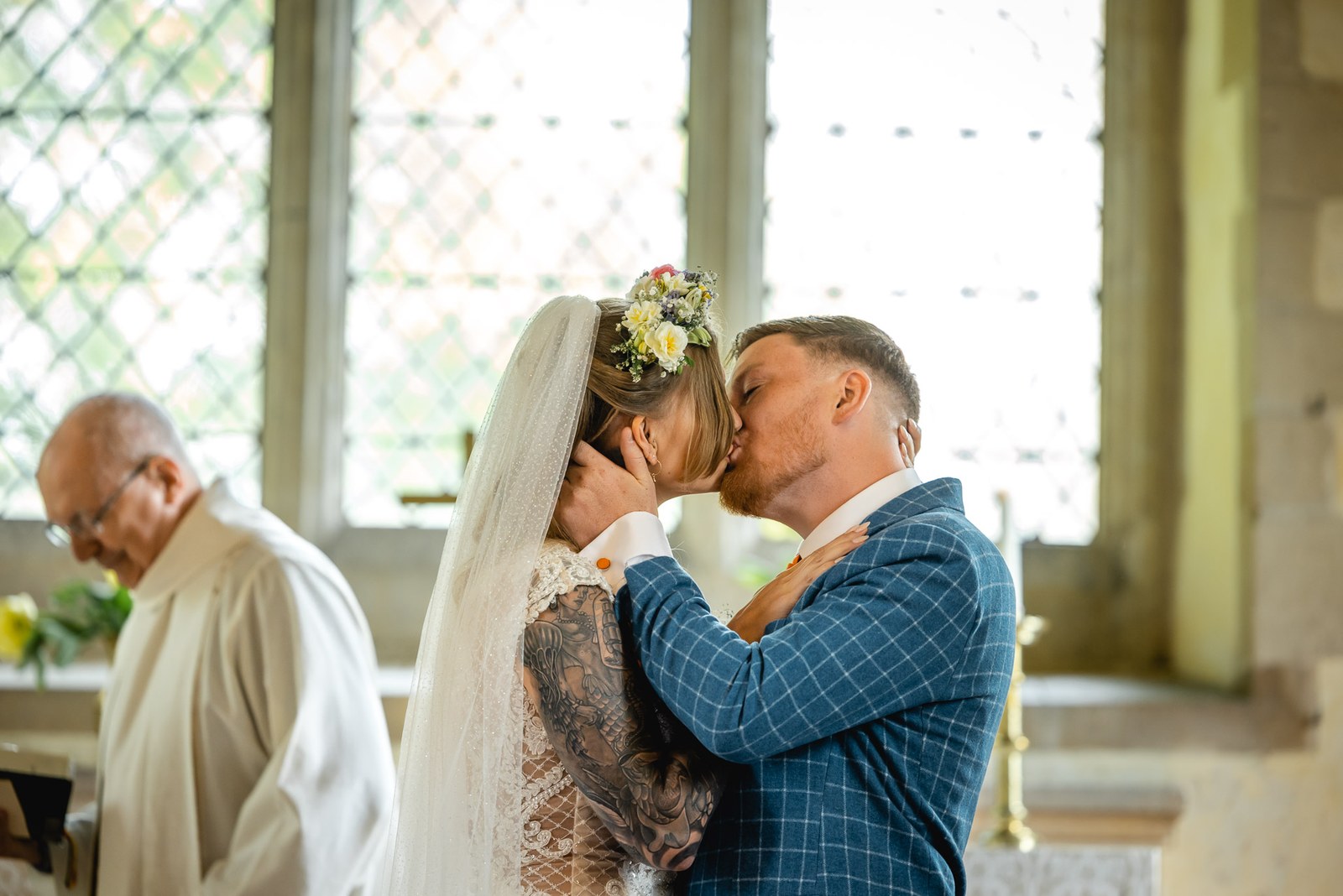 Bride and groom sharing their first kiss beside the vicar