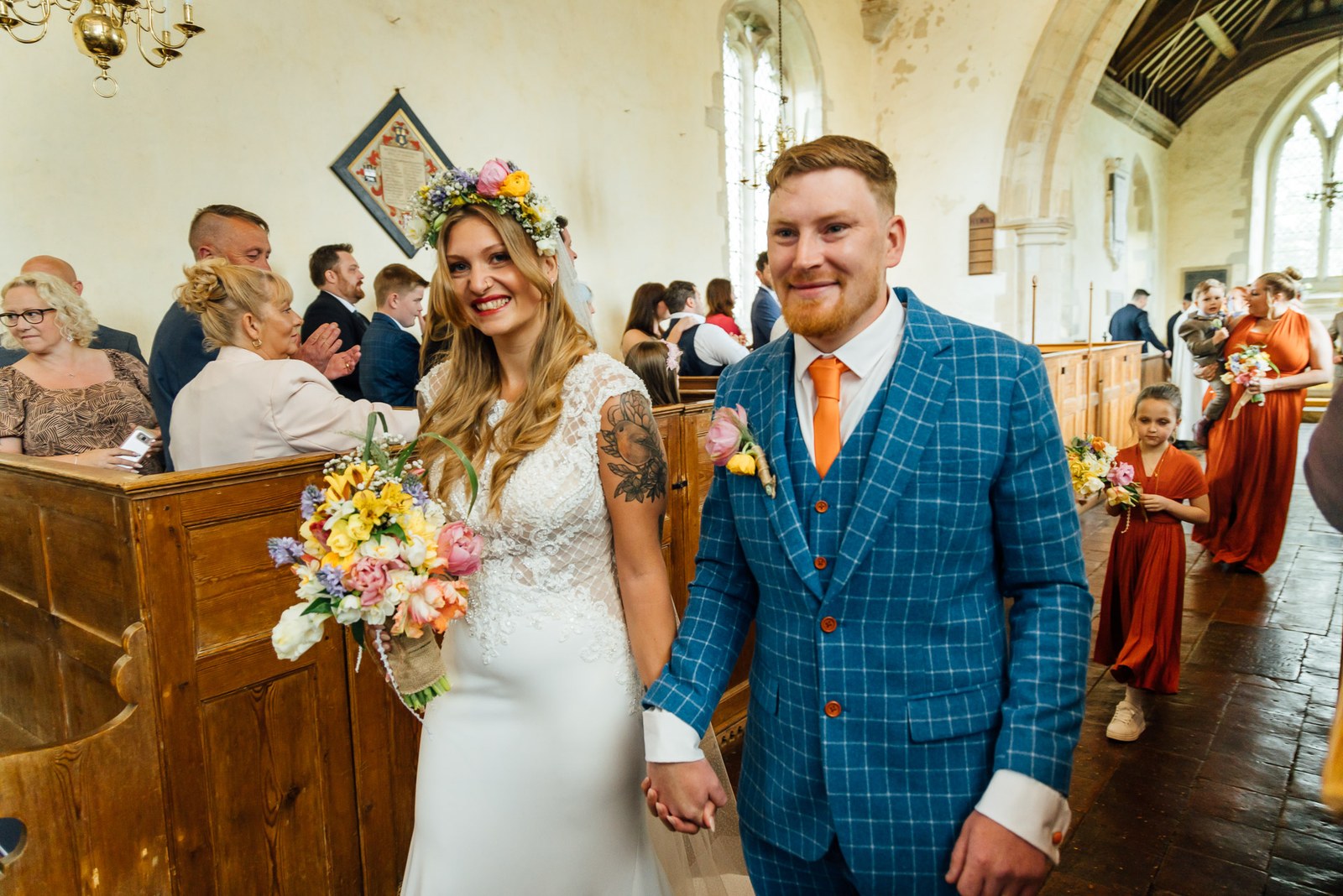 The smiling newlyweds processing out as guests applaud in the panelled church