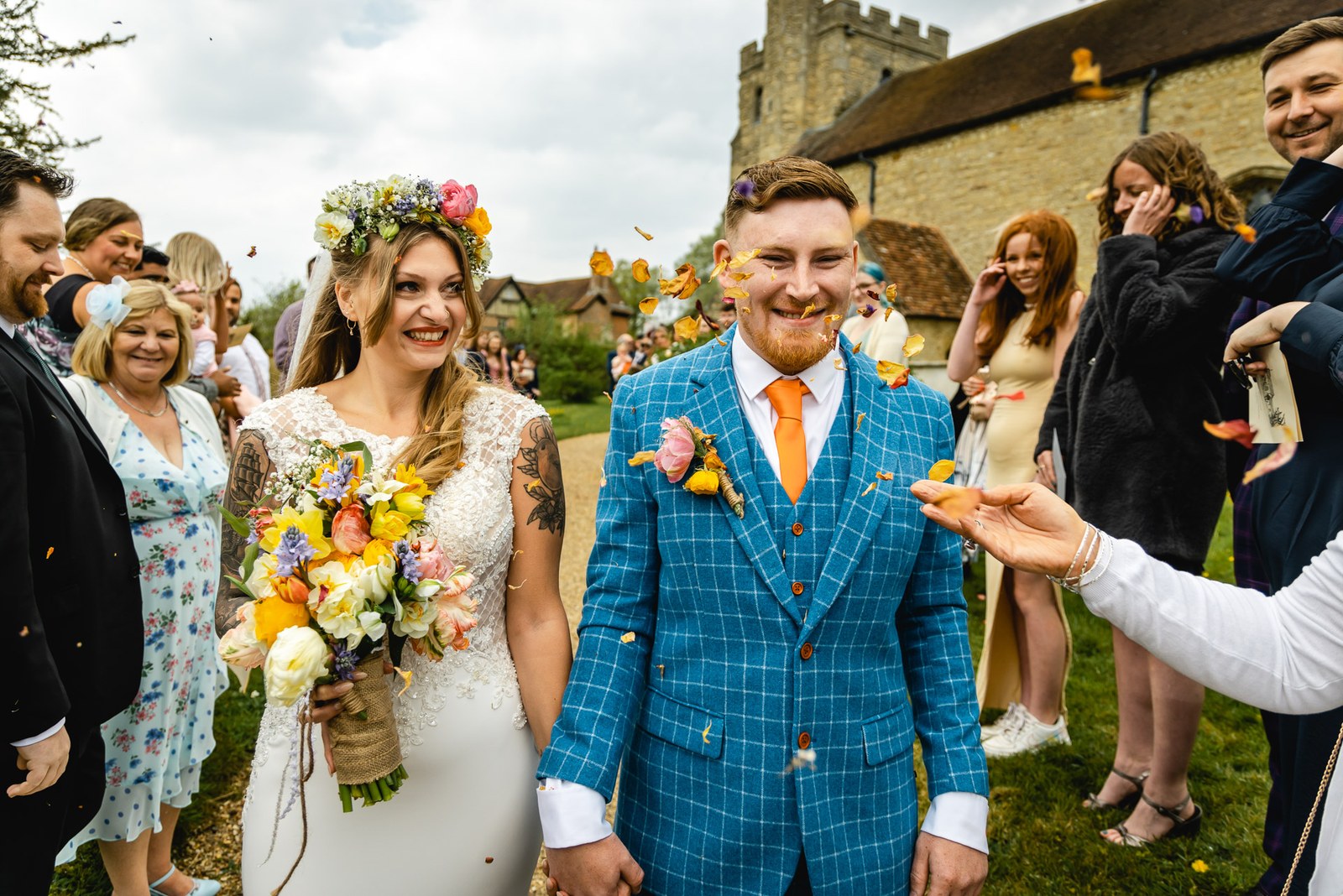 Bride and groom walking through confetti outside the church, the tower behind