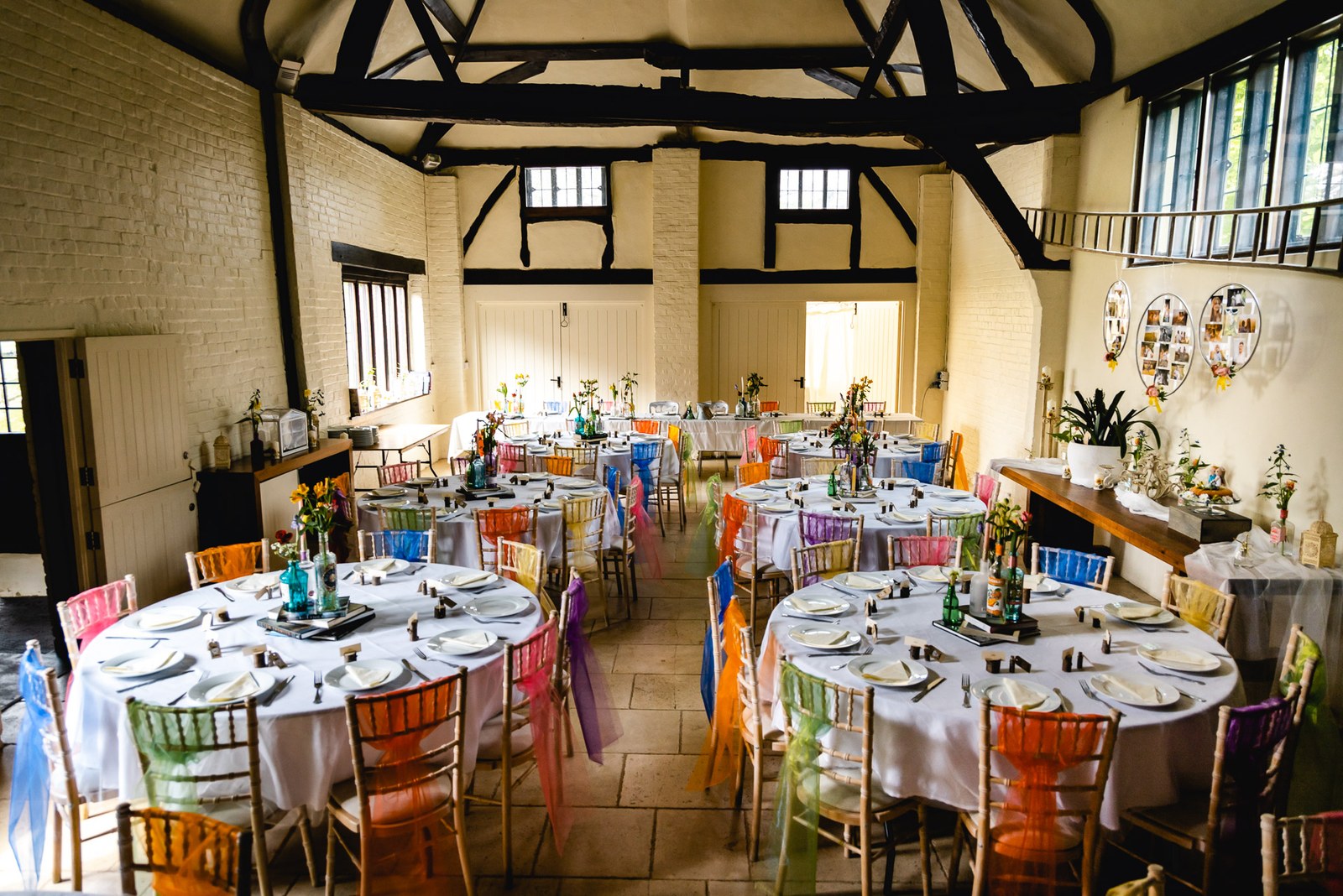 The timber-beamed reception hall set with round tables and rainbow chair sashes