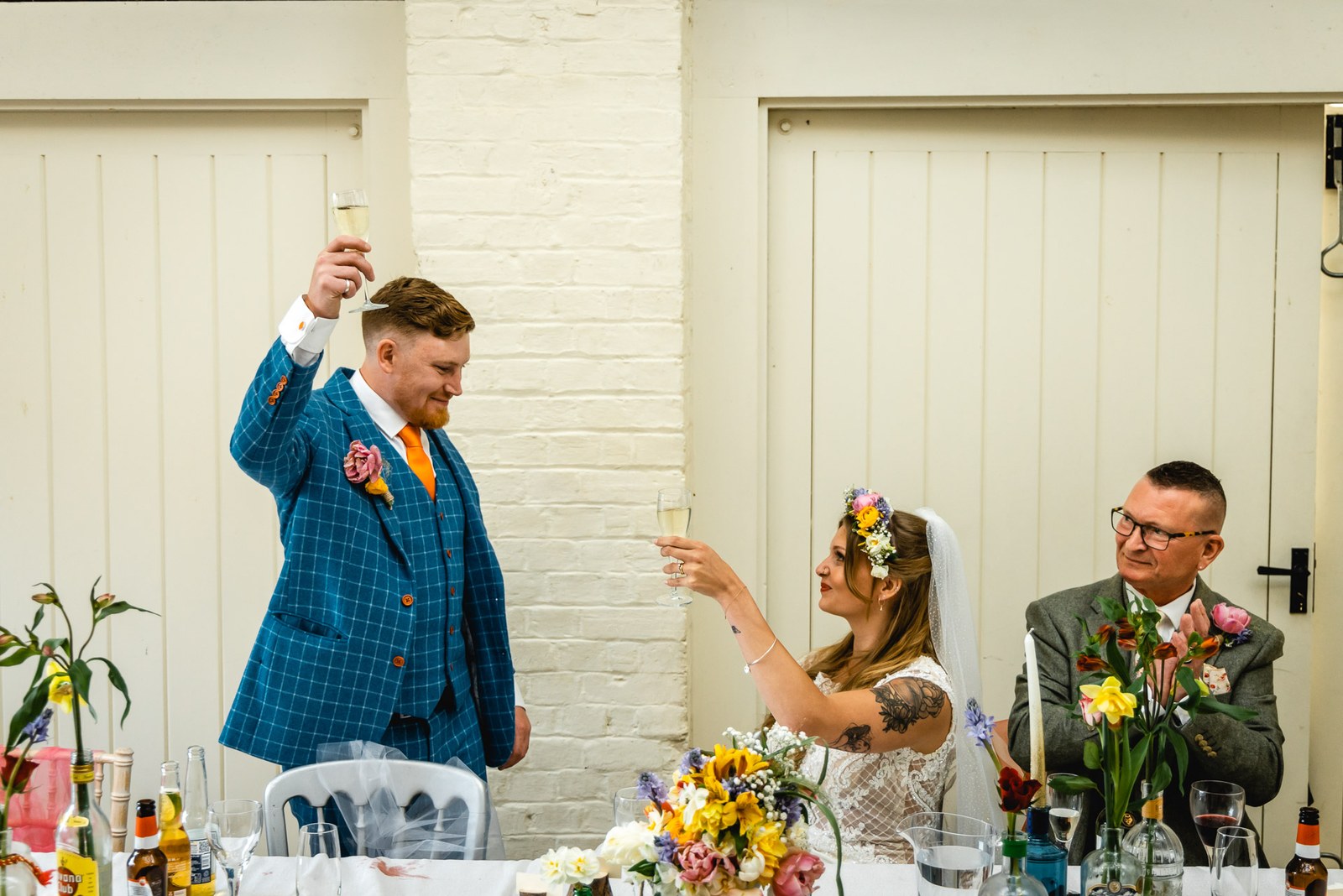 Groom raising a glass at the top table, the bride beside him