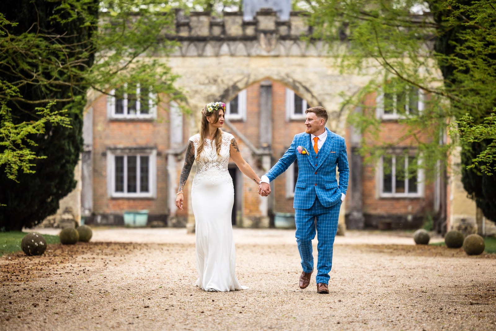 Bride and groom walking hand in hand down the drive of Nether Winchendon House