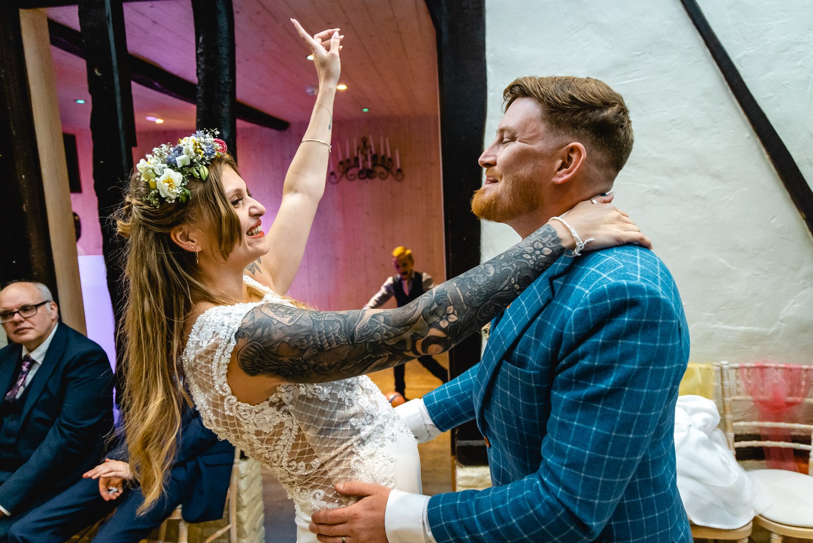 Bride with an arm raised dancing with the groom as guests watch