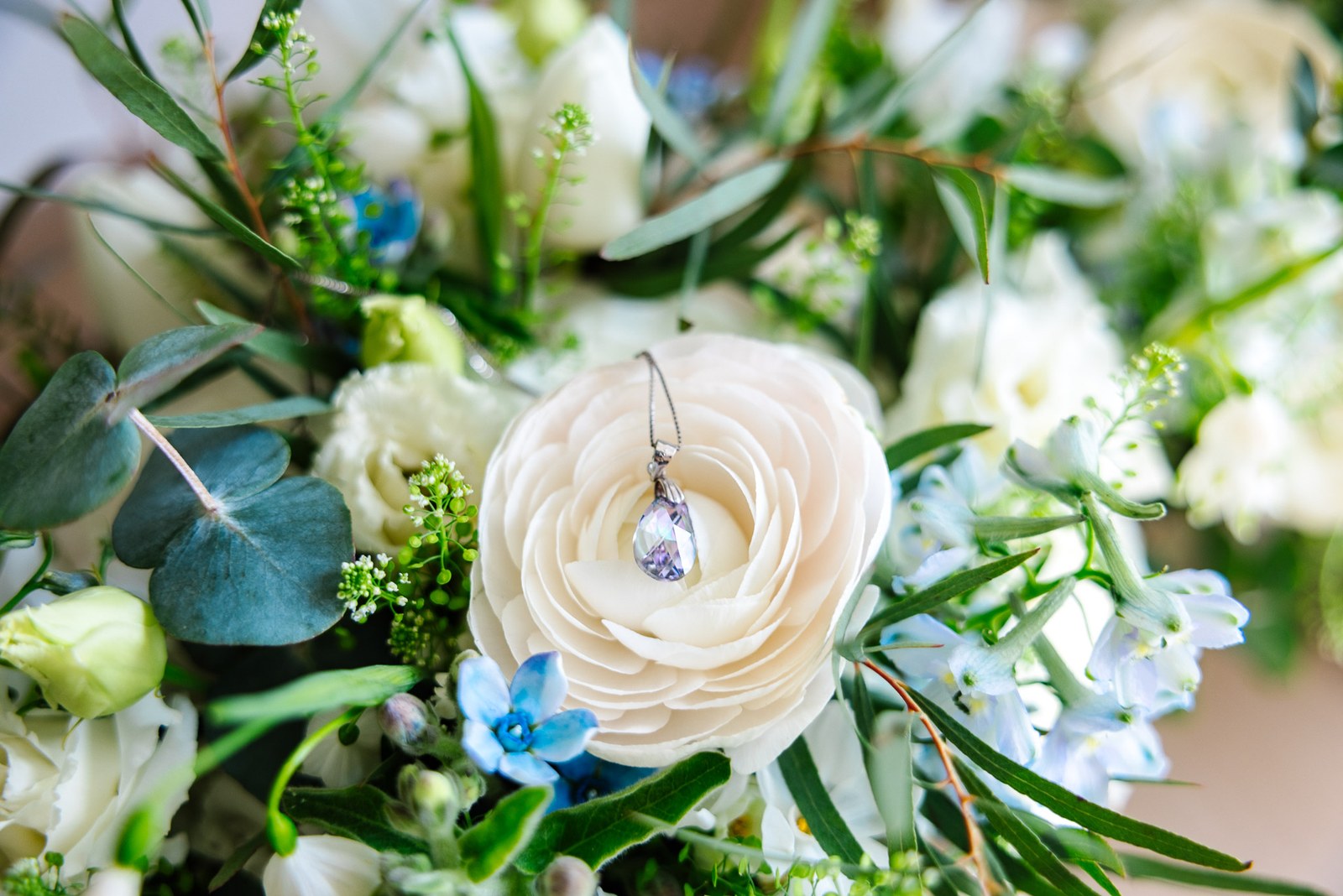 Close-up of the bride's bouquet with a teardrop crystal charm pinned to a white rose