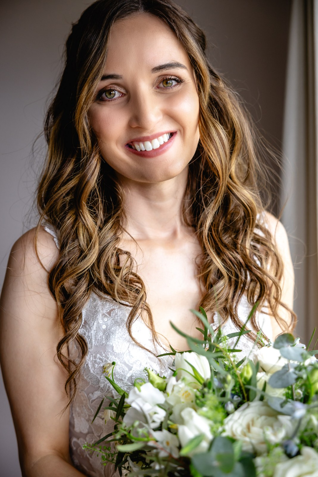 Portrait of the smiling bride holding her white and green bouquet