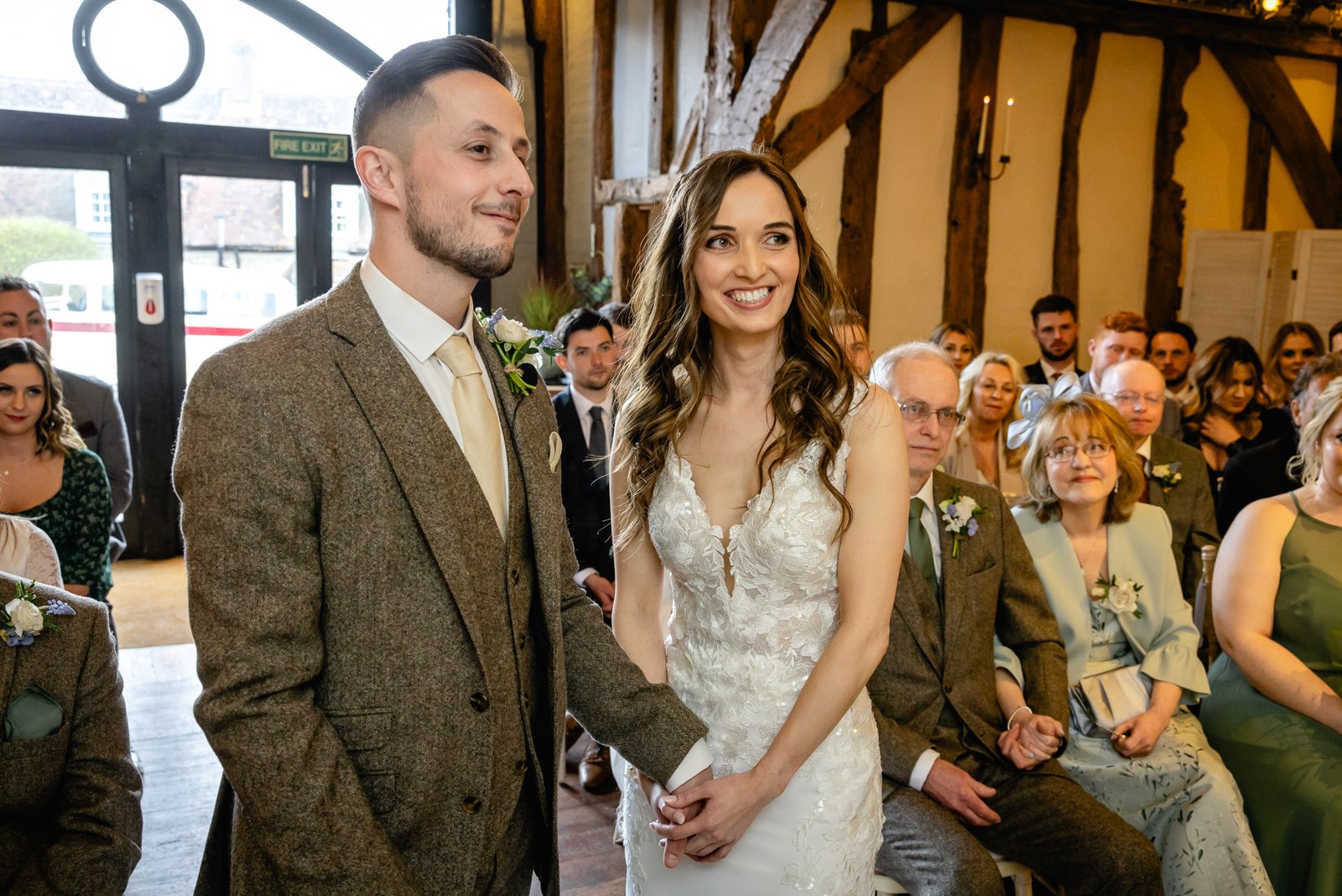 Bride and groom at the front of the timber-beamed barn as guests look on