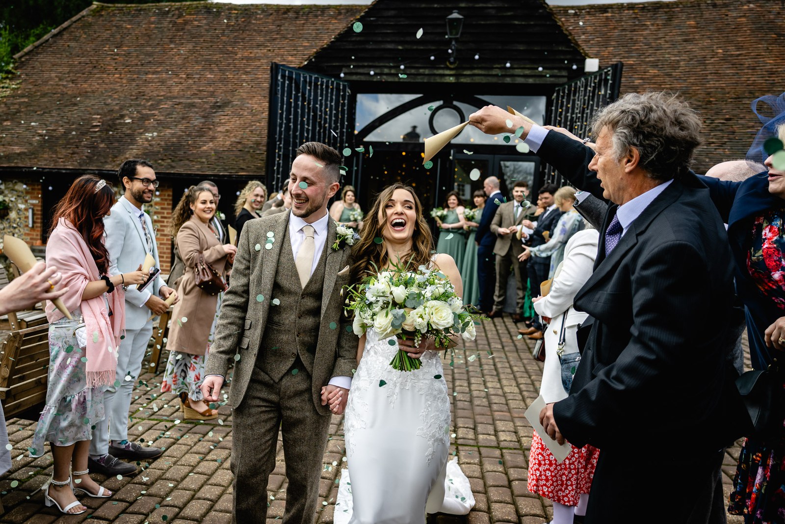 Bride and groom leaving Old Luxters Barn into a shower of confetti