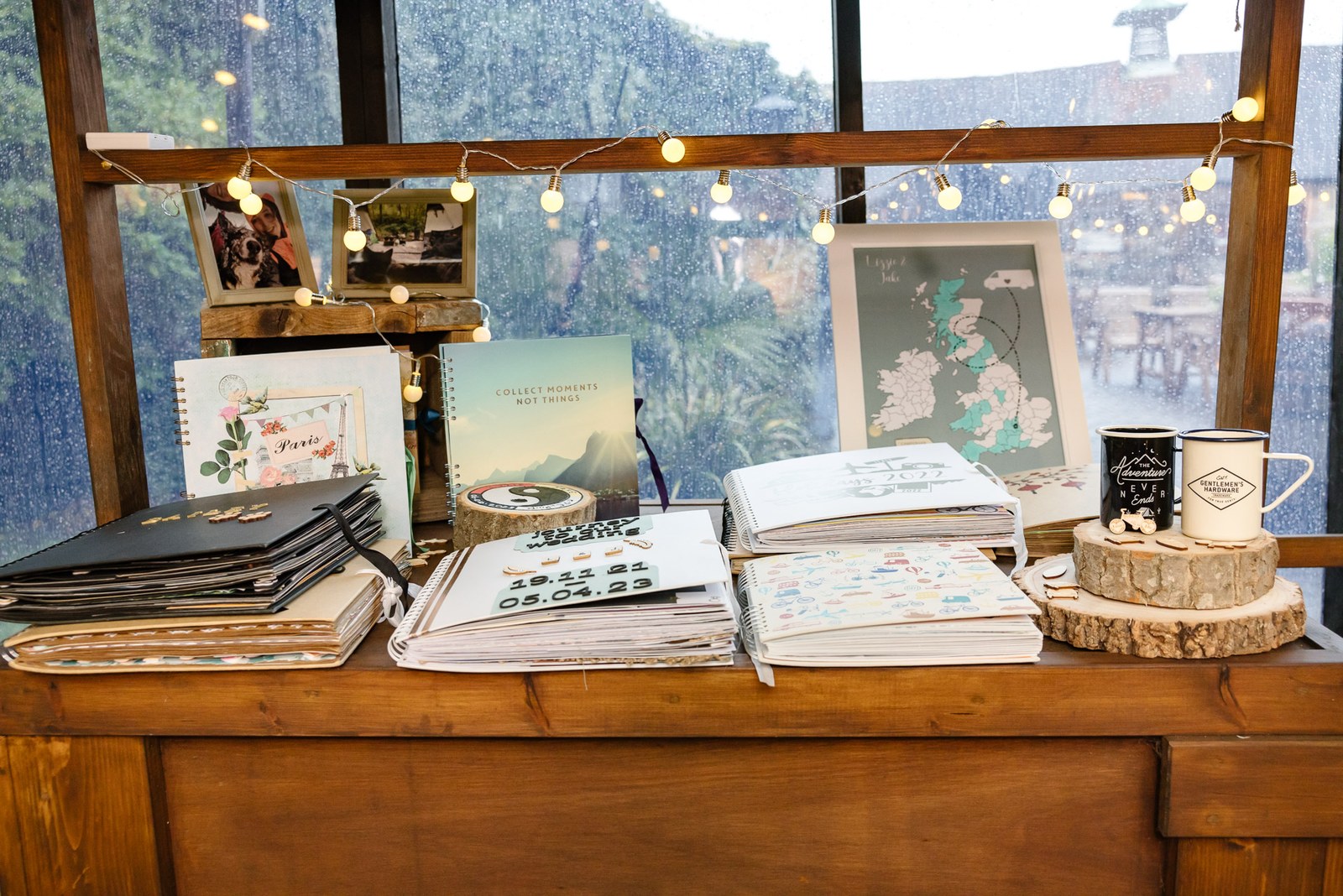 A rustic guest-book table with photos, fairy lights and a dated wood slice