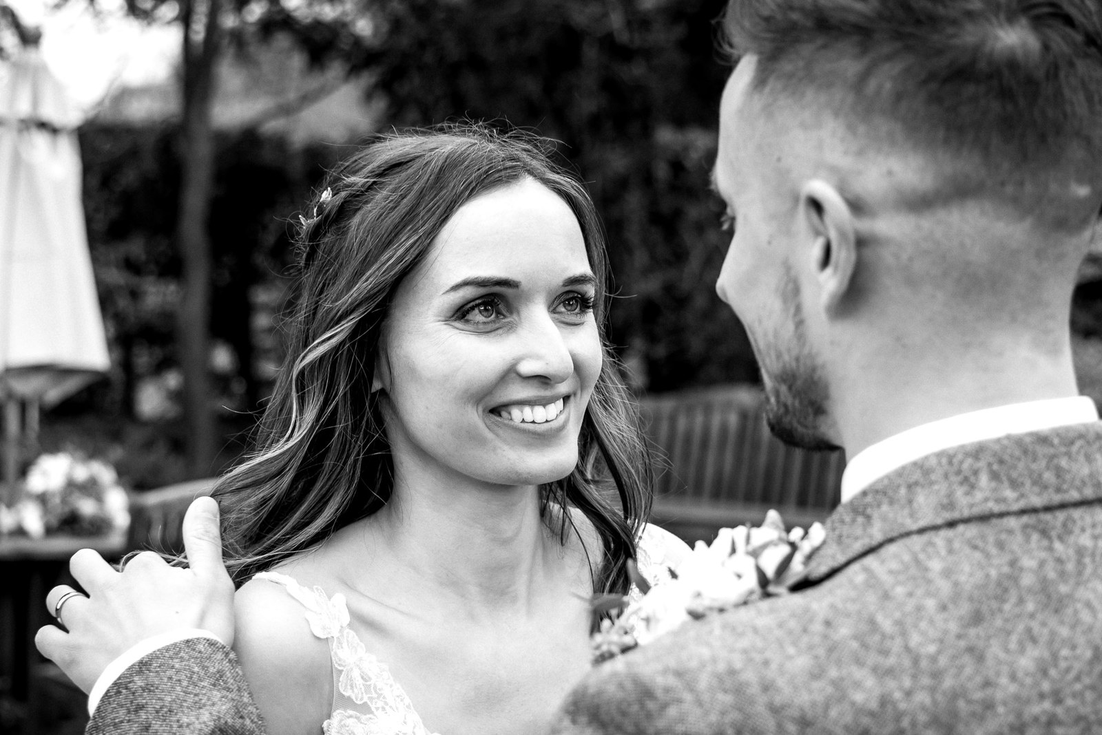 Black and white of the bride and groom smiling at each other outdoors