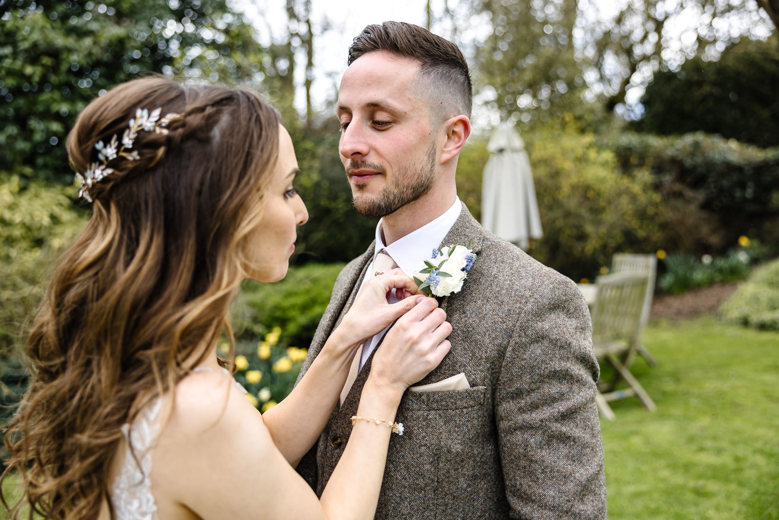 Bride adjusting the groom's buttonhole in the garden
