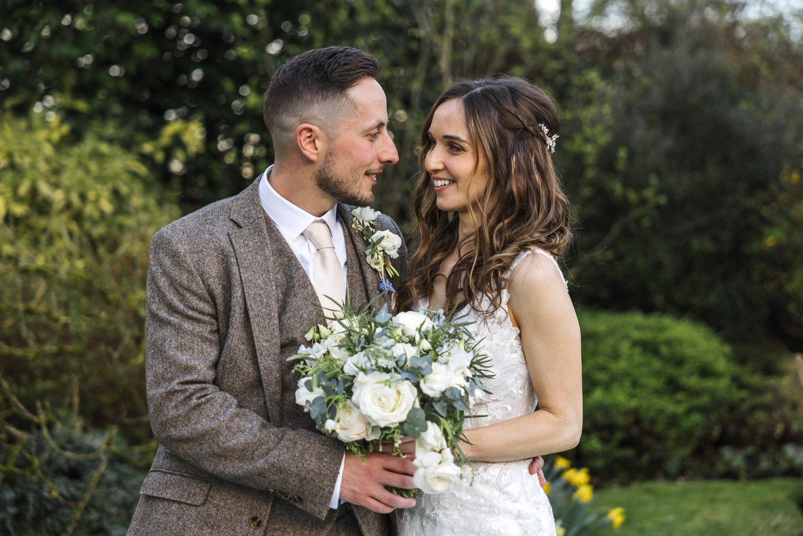 Bride and groom looking at each other in the garden, bouquet in hand
