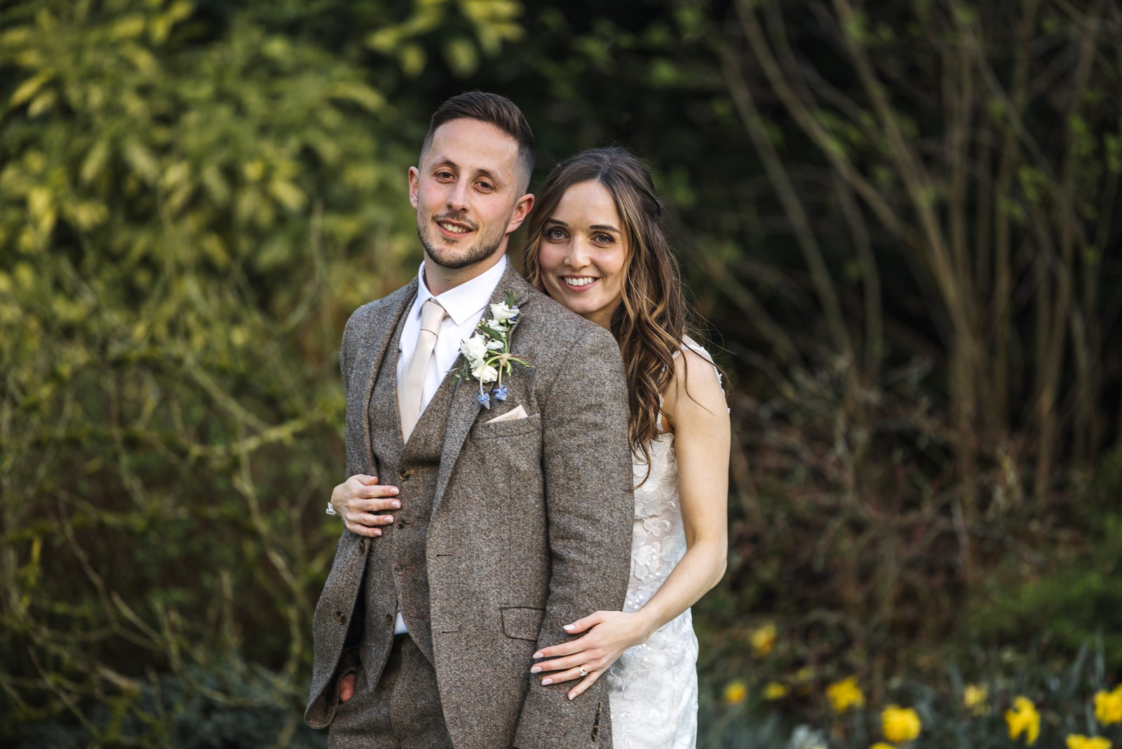 Bride and groom embracing among the daffodils in the garden