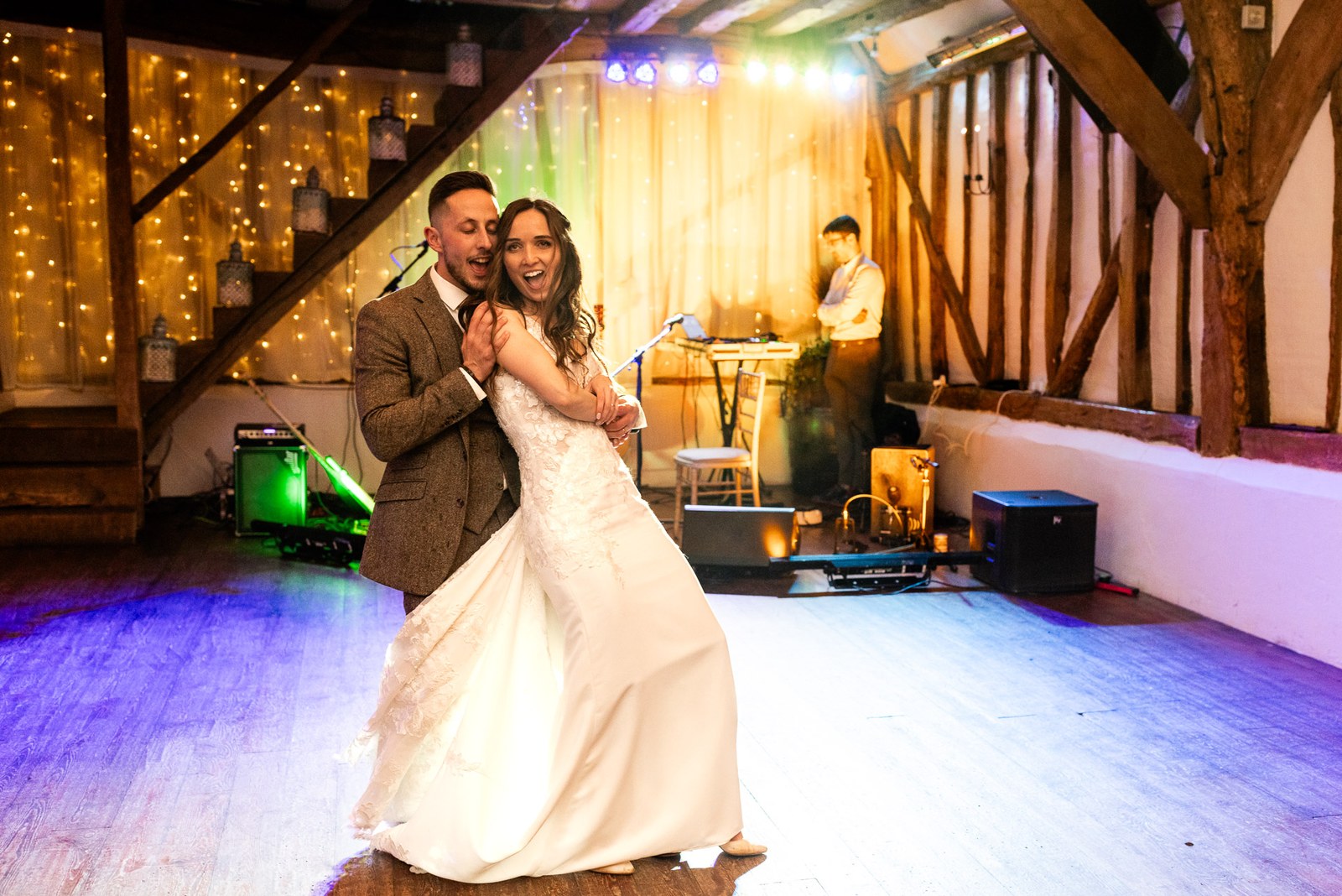 Bride and groom's first dance in the barn beneath fairy lights