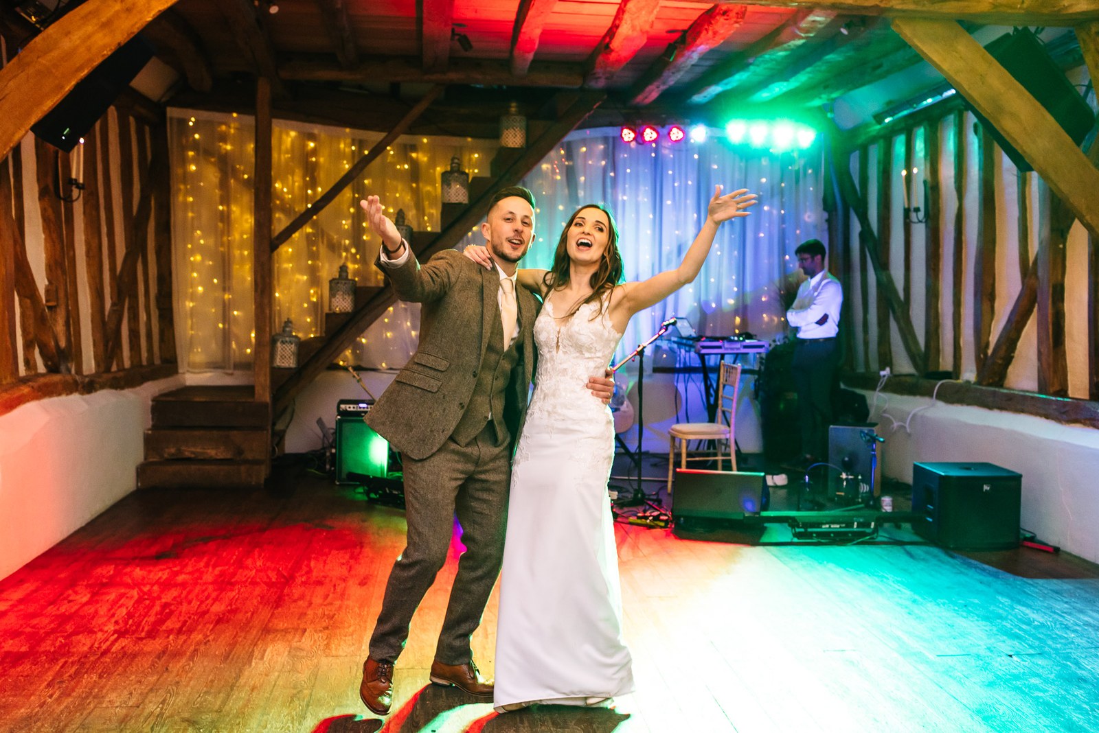The couple on the dance floor with arms outstretched under colourful lights