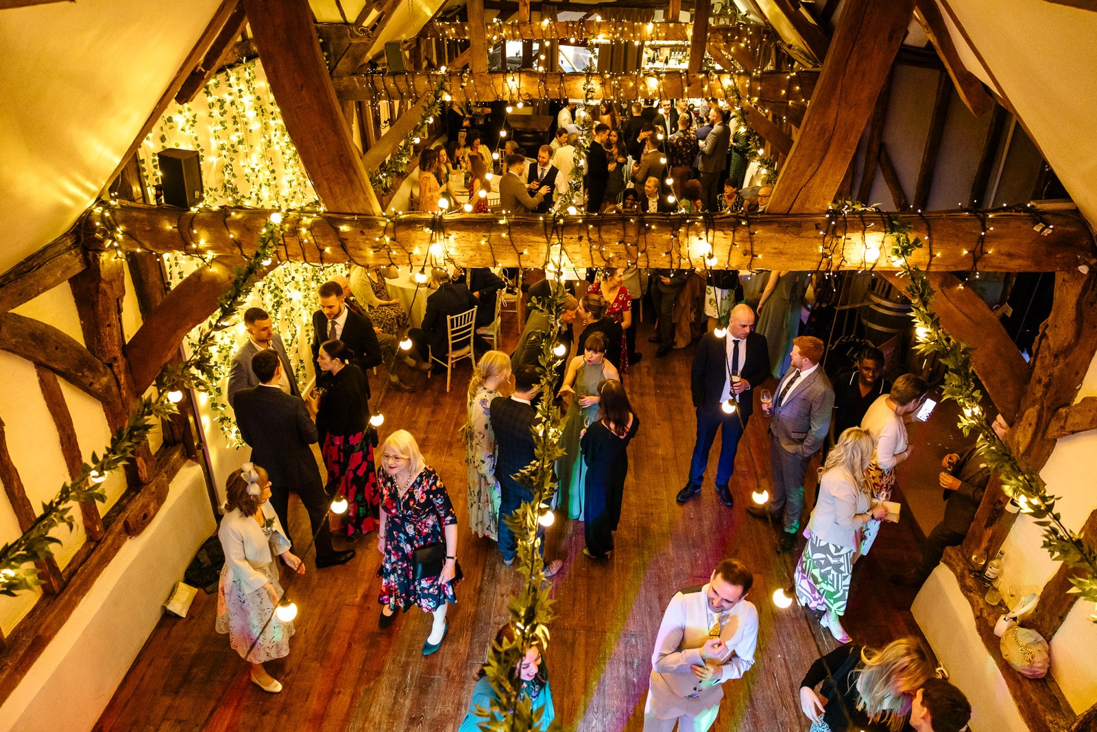 Elevated view of guests gathered in the timber barn under fairy lights