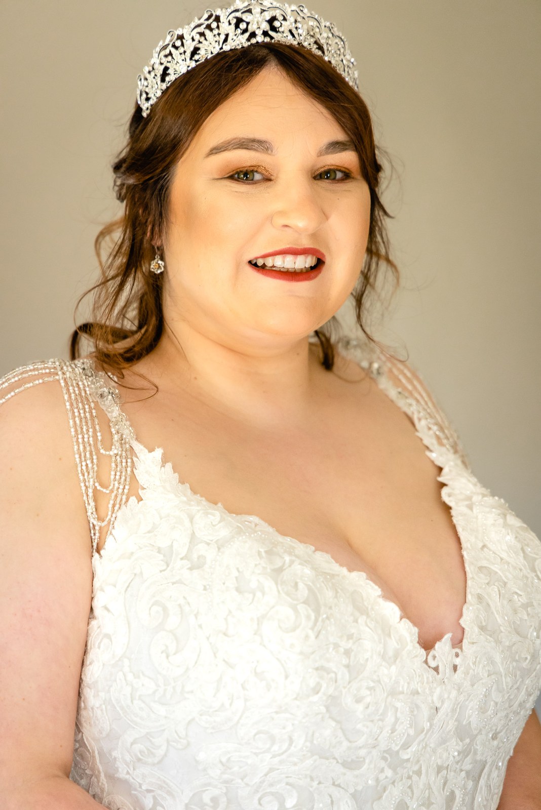 Portrait of the bride smiling, wearing a crystal tiara and beaded lace gown