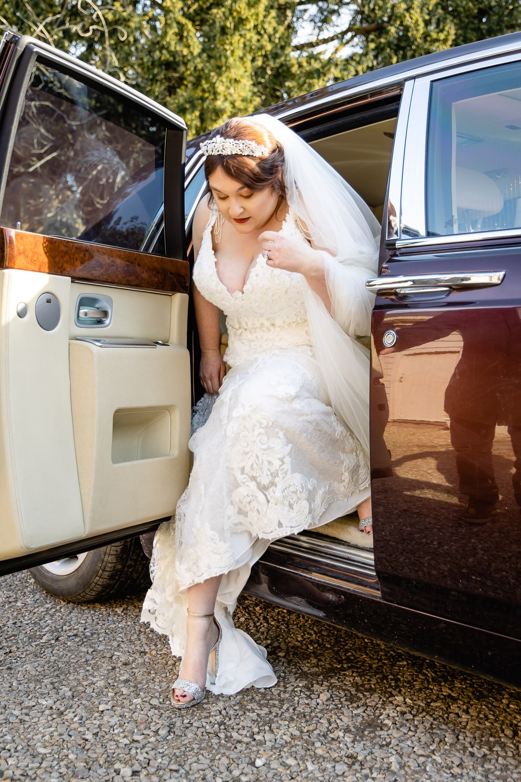 The bride stepping out of a Rolls-Royce in her gown and veil