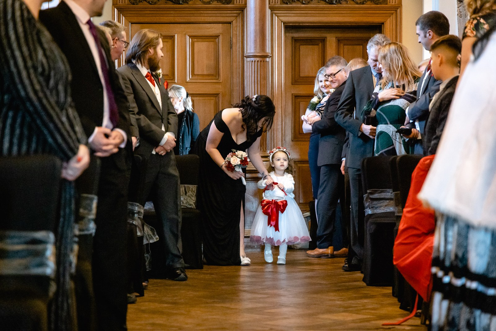 A flower girl walking down the aisle as guests look on
