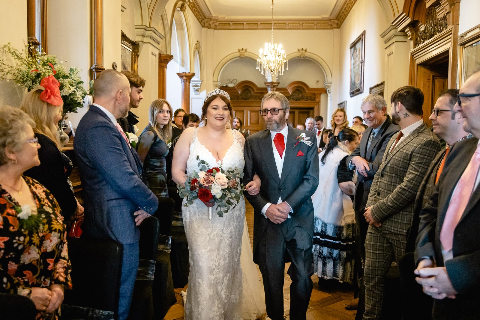 The bride walking down the aisle on an escort's arm between standing guests