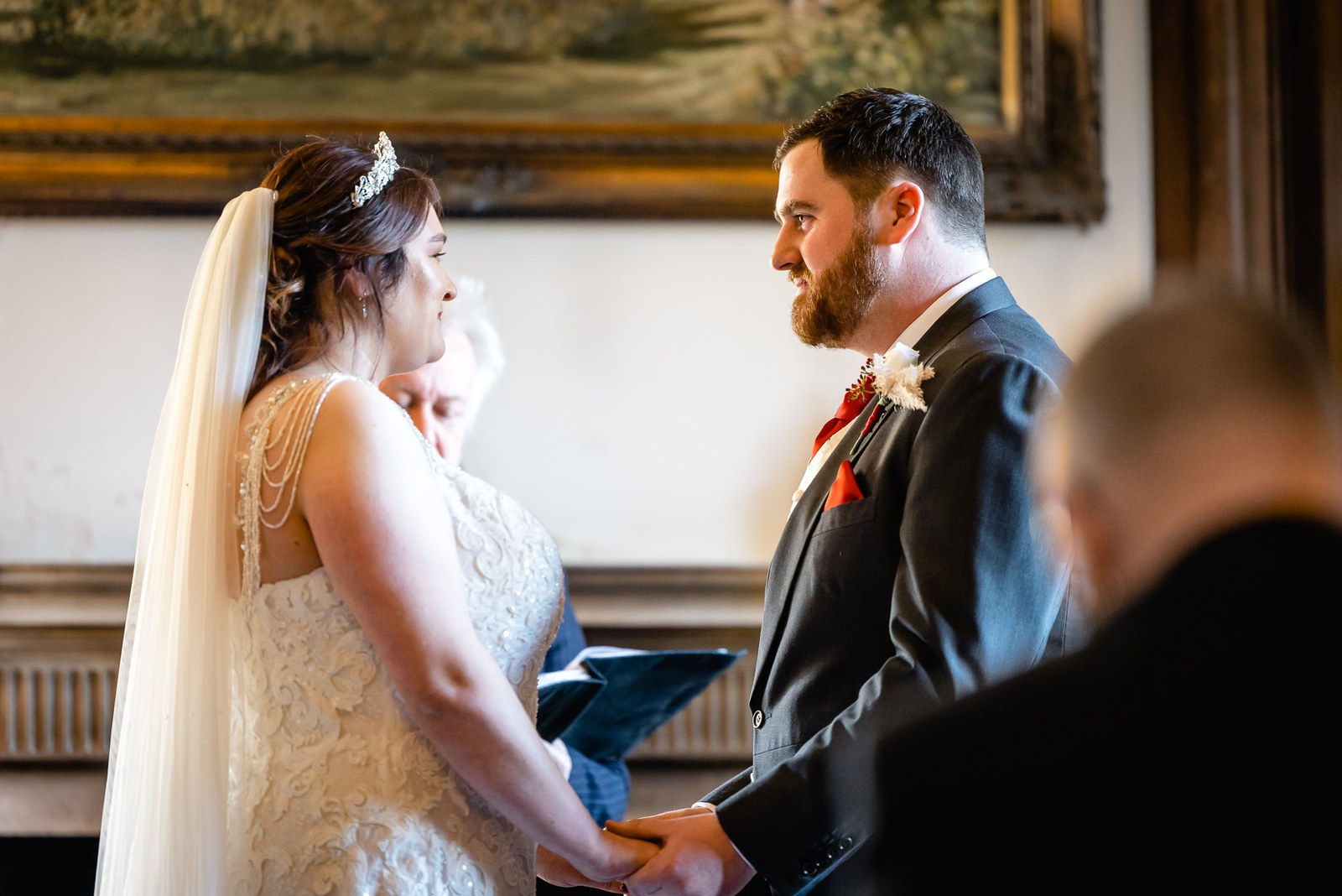 The couple holding hands during the ceremony, the bride shown in profile