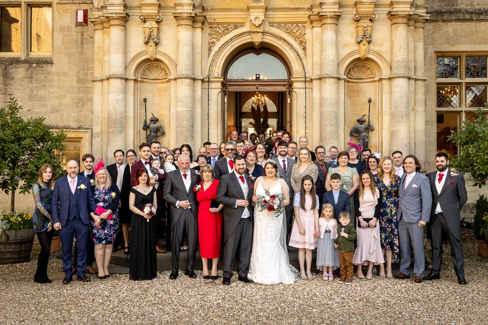 The full wedding party gathered before the honey-stone frontage of Orchardleigh House