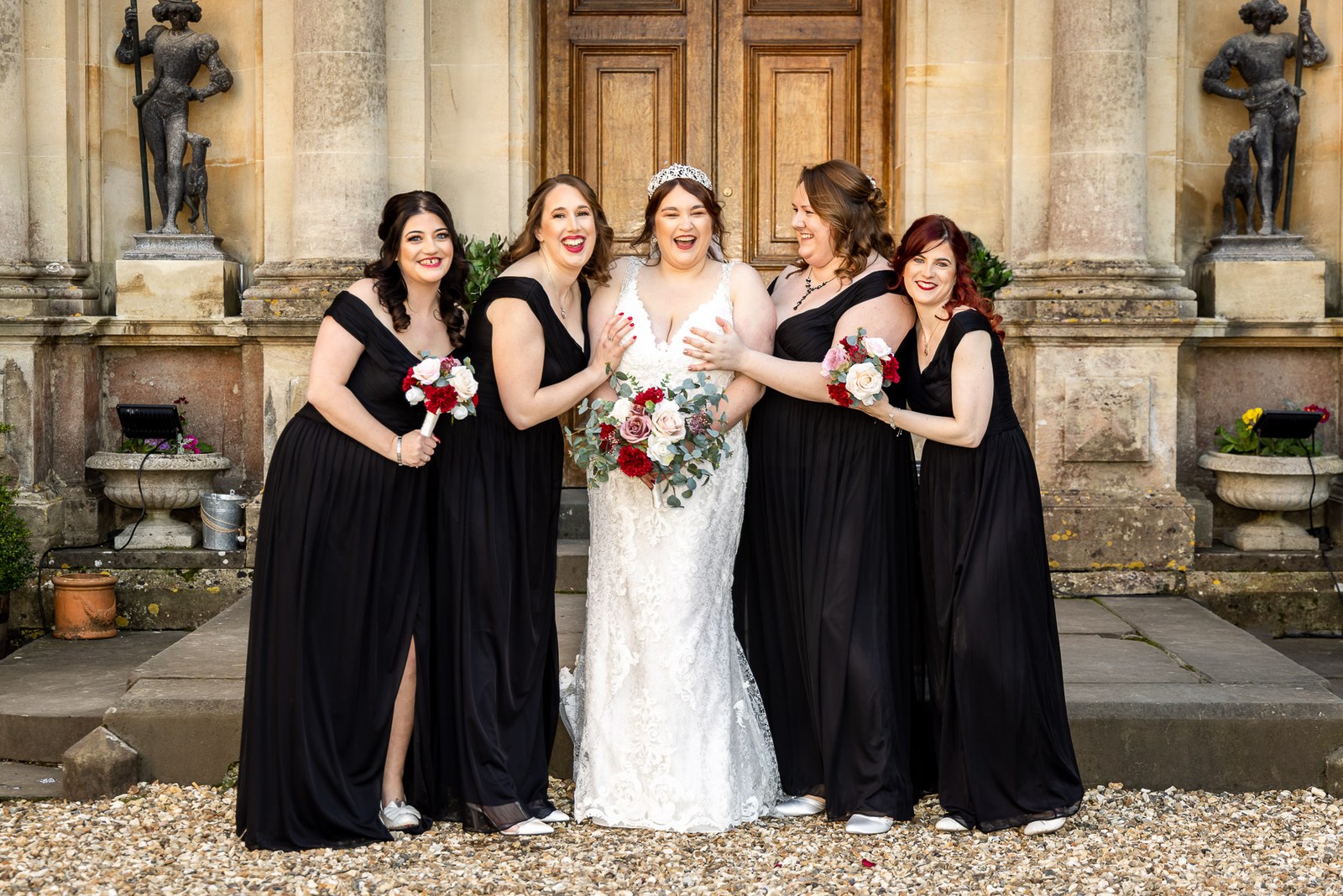The bride laughing with her bridesmaids in black gowns outside the house