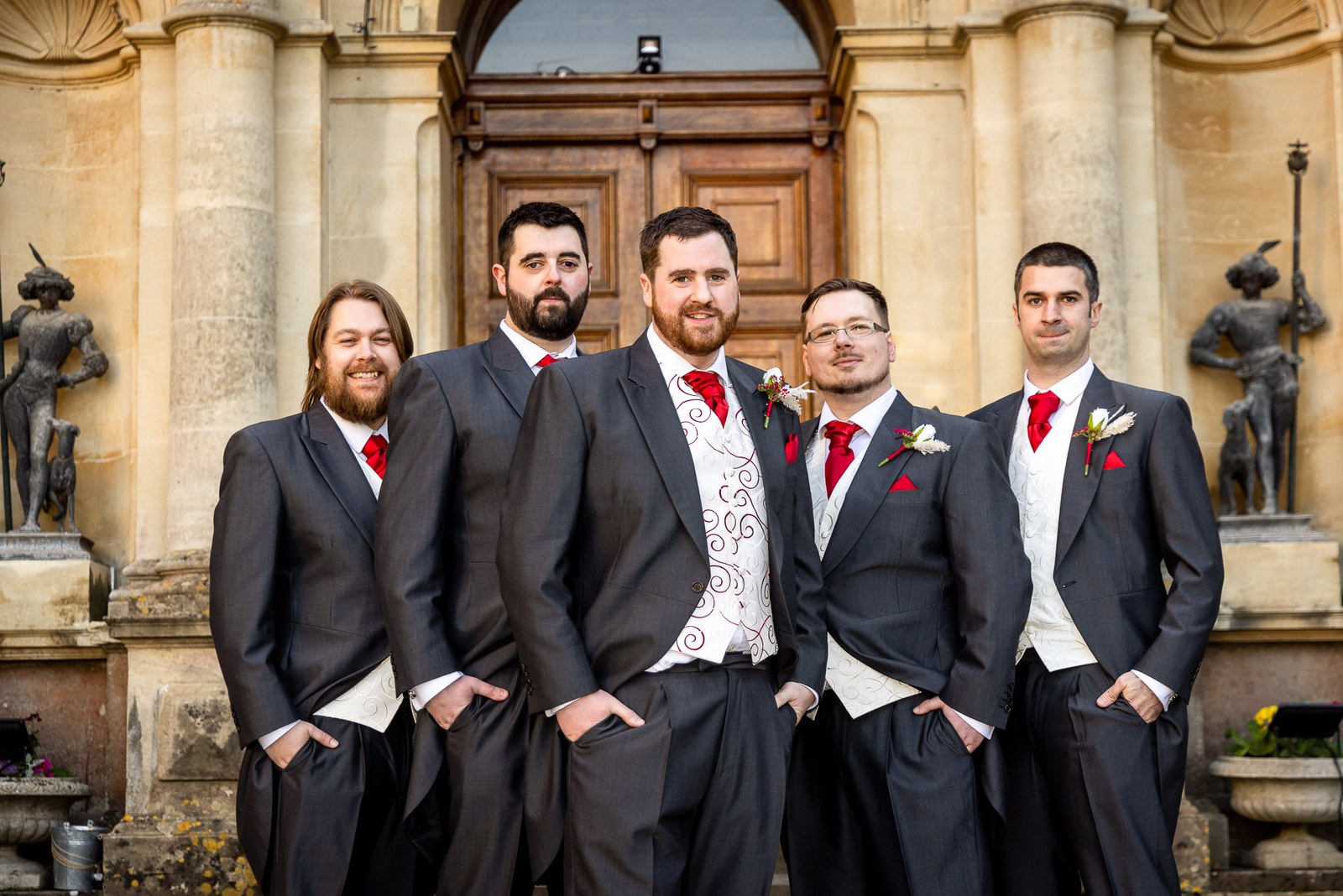 The groom and groomsmen posing before the grand entrance of Orchardleigh House