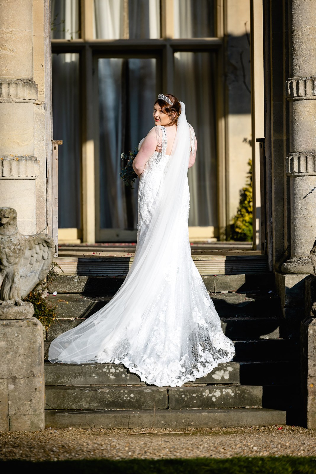 The bride on the steps of Orchardleigh House, her long veil and train spread out