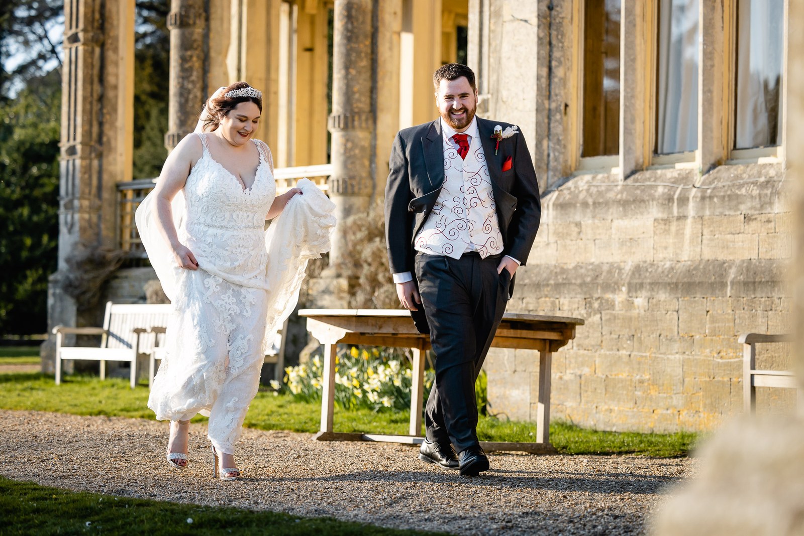 The couple walking past the honey-stone facade of Orchardleigh House by a garden bench