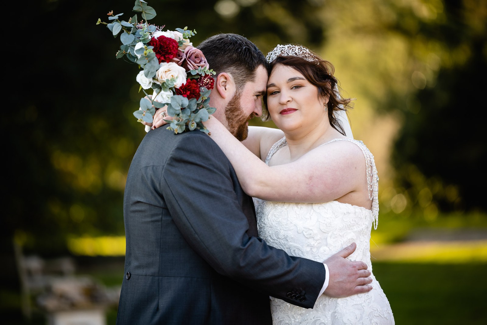 The couple resting their foreheads together, the bouquet raised beside them